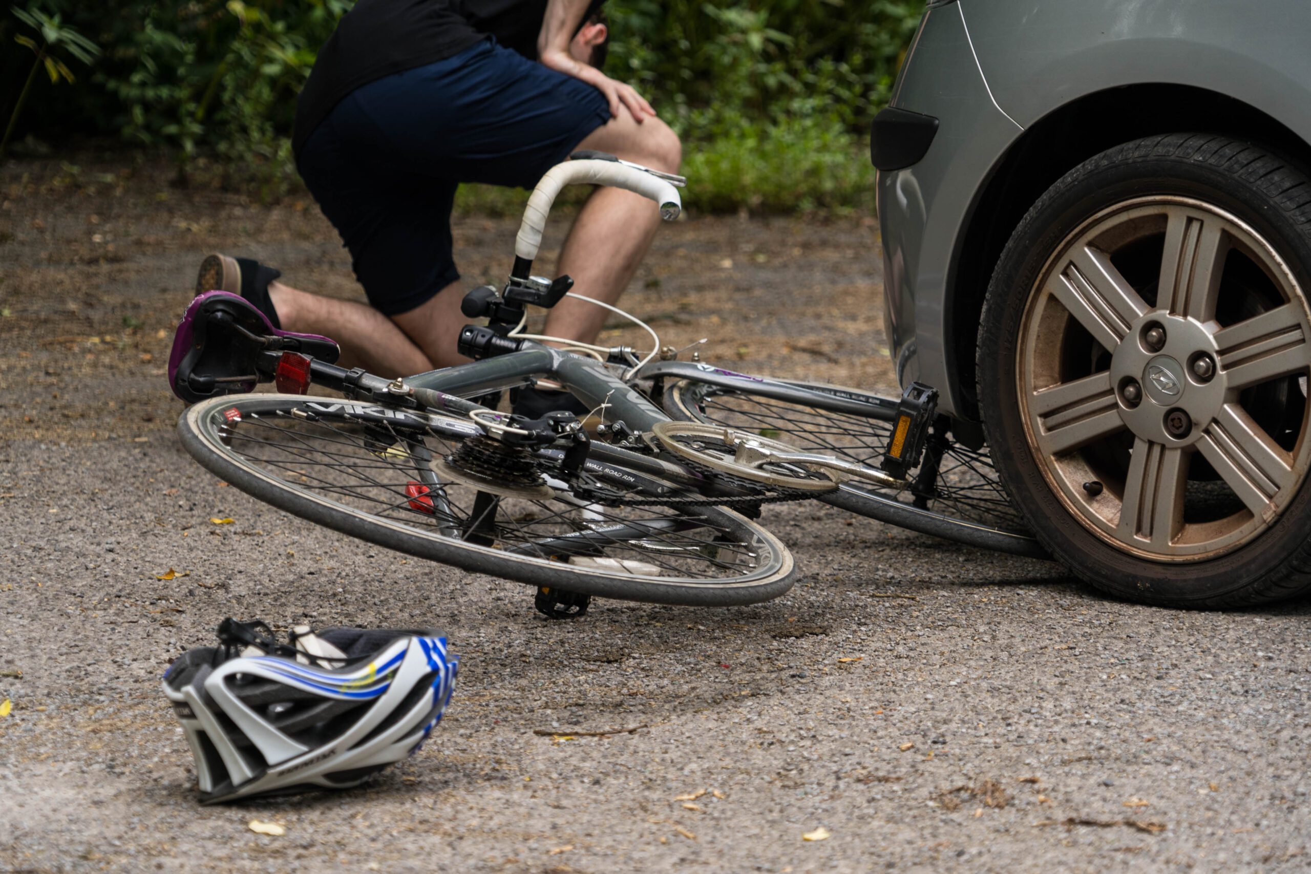 cyclist hurt after getting struck by a gray sedan on a dirt road